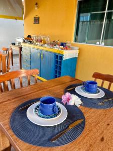 a wooden table with two blue cups and plates on it at Samburá Suítes in Japaratinga