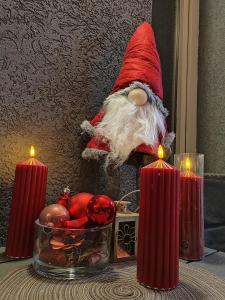 een kerstman beeldje zittend op een tafel met kaarsen bij Bed and Breakfast Majesty in Niš