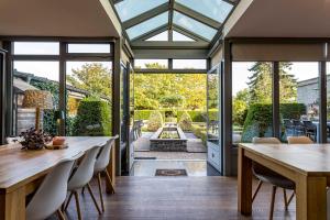 a conservatory with a dining room with a table and chairs at ZussEnzo - STOER FAMILIEHUIS - 18P - 5SLPK - GROTE TUIN - SAUNA - OFYR BBQ - HOMECINEMA - 15MIN MAASTRICHT in Zussen