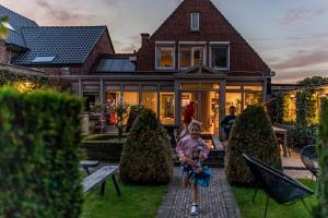 a young child standing in front of a house at ZussEnzo - STOER FAMILIEHUIS - 18P - 5SLPK - GROTE TUIN - SAUNA - OFYR BBQ - HOMECINEMA - 15MIN MAASTRICHT in Zussen