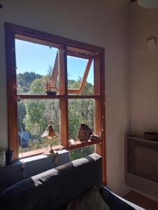 a room with a window with a couch and a lamp at Casita en el bosque in San Carlos de Bariloche