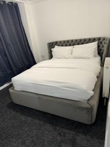 un letto con lenzuola e cuscini bianchi di LUXURY APARTMENTS a Dagenham