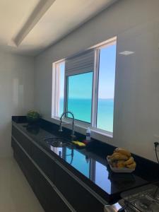 cocina con encimera con fregadero y 2 ventanas en COBERTURA com belíssima vista para o mar e jacuzzi, en Itapema