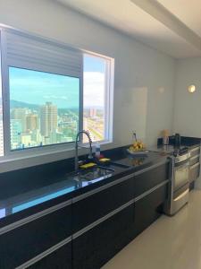 una cocina con encimeras negras y una ventana grande en COBERTURA com belíssima vista para o mar e jacuzzi, en Itapema
