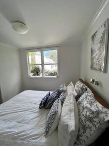 een slaapkamer met een bed met kussens en een raam bij Herne Bay 1 Bedroom Apartment - Stay Auckland in Auckland