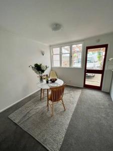 een witte kamer met een tafel en stoelen en een raam bij Herne Bay 1 Bedroom Apartment - Stay Auckland in Auckland