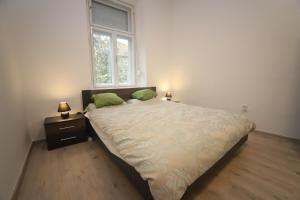 uma cama num quarto com uma janela e dois candeeiros em Ibolya Apartman Szeged em Szeged