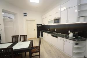 uma cozinha com armários brancos e uma mesa e cadeiras em Ibolya Apartman Szeged em Szeged