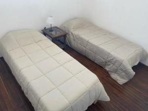two beds in a room with a side table at Departamento Avenida in Santo Tomé