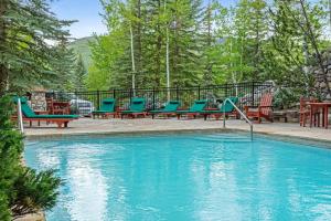 uma piscina com cadeiras azuis, mesas e árvores em Saddleridge Villas #3 em Beaver Creek
