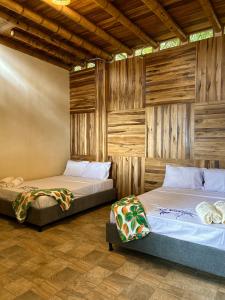 two beds in a room with wooden walls at La Veranda Hotel & Restaurant in Minca