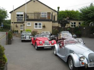 three old cars parked in front of a house at Holly Tree B&B in Bromyard