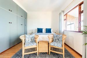 a bedroom with a bed and two chairs at Innie Baai Beach House in Cape Town