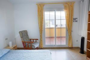 ein Schlafzimmer mit einem Bett und einem Stuhl und einem Fenster in der Unterkunft Piscina playa y relax en familia in Roquetas de Mar + 4 Fotos