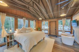 a bedroom with a bed and a bath tub and windows at Bonners Ferry Cabin with Wraparound Deck and Views! in Bonners Ferry