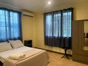 a bedroom with a large bed with blue curtains at Samoa Business Apartments in Apia