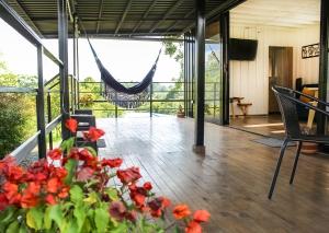 a porch with red flowers and a hammock at Hospedaje Santa Ana in Circasia