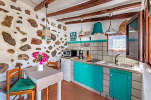 a kitchen with blue cabinets and a table with a sink at Las Casas de la Rueda - La Casita in Santa Lucía