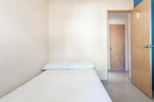 a white bed in a small room with a door at CASA TURISTICA MACHU PICCHU MEDELLIN in Medellín