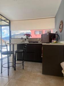 a kitchen with a counter and chairs and a table at Suite Independiente e íntima al Norte de Quito in Quito