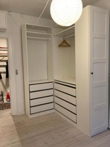 a walk in closet with white cabinets and a light at 400 m from metro modern cozy apartment in Copenhagen