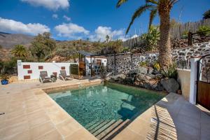 una piscina en un patio trasero con una palmera en Las Casas de la Rueda - La Casita, en Santa Lucía