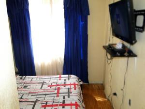 a bedroom with a bed and a tv and a window at GUESTHOUSE MOUNTAIN TRAVEL ECUADOR 