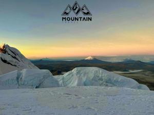 einen schneebedeckten Berg mit den Bergen im Hintergrund in der Unterkunft GUESTHOUSE MOUNTAIN TRAVEL ECUADOR 