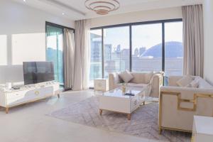 sala de estar con muebles blancos y ventana grande en Vendome Apartment Lusail, en Lusail