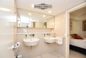 Baño con 2 lavabos y espejo en "NEWQUAY" Ideal Location & Views at PenthousePads en Darwin