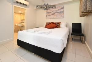 um quarto com uma grande cama branca e uma cadeira preta em "NEWQUAY" Ideal Location & Views at PenthousePads em Darwin