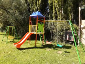un parque infantil con columpios en el césped en Cabañas Amalar en Malargüe