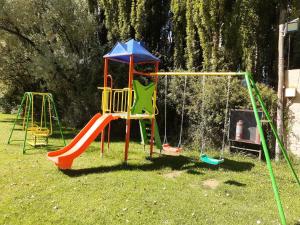 a playground with a swing set in the grass at Cabañas Amalar in Malargüe