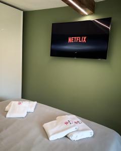 due asciugamani su un letto con televisore a muro di Bel Fiore Deluxe Apartment a Genova