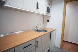 Una cocina con gabinetes blancos y un fregadero. en EUROPA HOUSE - Parking GRATIS, en Sierra Nevada