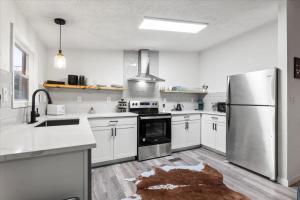 une cuisine avec des armoires blanches et un réfrigérateur en acier inoxydable dans l'établissement Starlight Horizon Cabin K - Pet-Friendly Texas Hill Country Cabin Near Canyon Lake - Pool, Stargazing & Group Getaways - Sleeps 8, à Canyon Lake