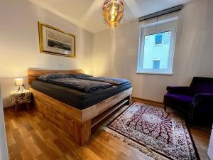 a bedroom with a bed and a chair and a window at Ferienwohnung im Sonnendorf Öblarn in Öblarn