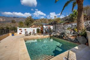a swimming pool in a backyard with a palm tree at Las Casas de la Rueda - El Patio in Santa Lucía