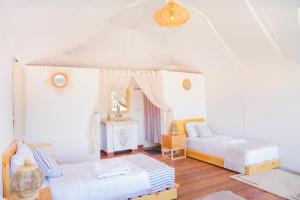 een witte kamer met 2 bedden en een bank bij Sahara Royal Resort in Merzouga