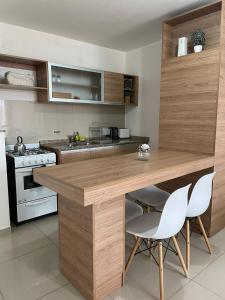 cocina con encimera de madera y sillas blancas en Departamento 1 Dormitorio, Edificio Vow en Villa Carlos Paz