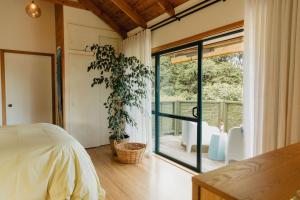 コロマンデルにあるBuffalo Lodgeのベッドルーム1室(ベッド1台付)、スライド式ガラスドアが備わります。