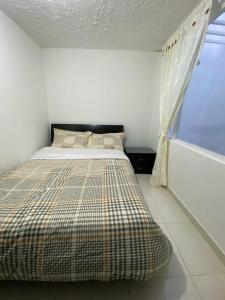 Cama en habitación blanca con ventana en Acogedor Apartamento Pequeño e Independiente, en Bogotá