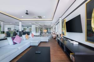 un soggiorno con mobili bianchi e TV a schermo piatto di Villa Sirion a Kamala Beach