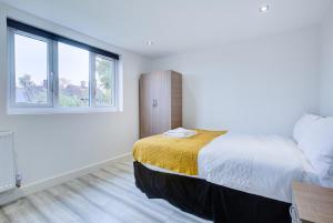 a bedroom with a large bed and two windows at CrossVille Homes - Double rooms in Navestock