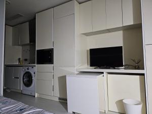 a kitchen with white cabinets and a washer and dryer at Urban Space Sinnonhyeon in Seoul