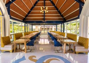 a cafeteria with wooden tables and blue chairs at Hotel Sinaí SV in Macanal