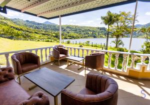 a balcony with chairs and a table and a view of a lake at Hotel Sinaí SV in Macanal
