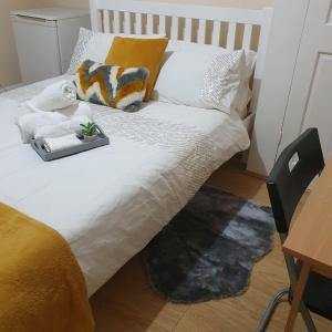 a bed with white sheets and a tray of pillows at Happy Dreams B in London