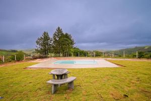 een bank in het midden van een veld met een zwembad bij Sítio Terra Sertaneja - Chalé Estou Apaixonado in Turvo dos Góis