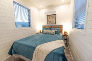 a bedroom with a bed with a blue comforter and two windows at New Southwest Shipping Container-In Alpine in Alpine